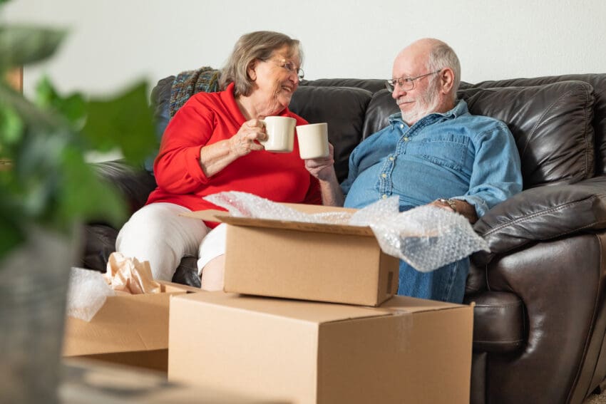 Tired,Senior,Adult,Couple,Resting,On,Couch,With,Cups,Of