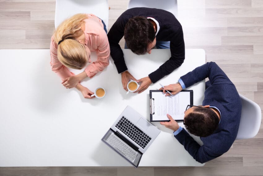 Happy,Young,Couple,Consulting,Male,Friendly,Financial,Advisor,With,Coffee